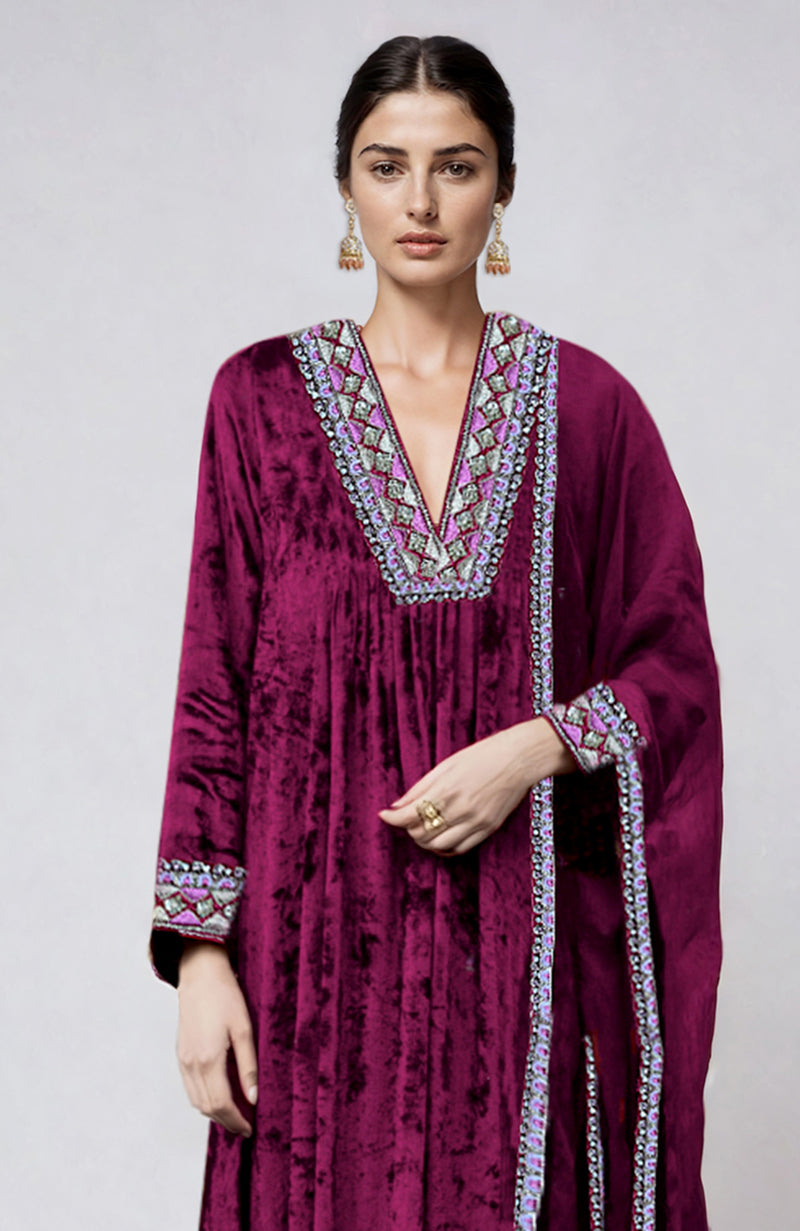 A woman models a bright rose velvet kurta set with intricate embroidery.