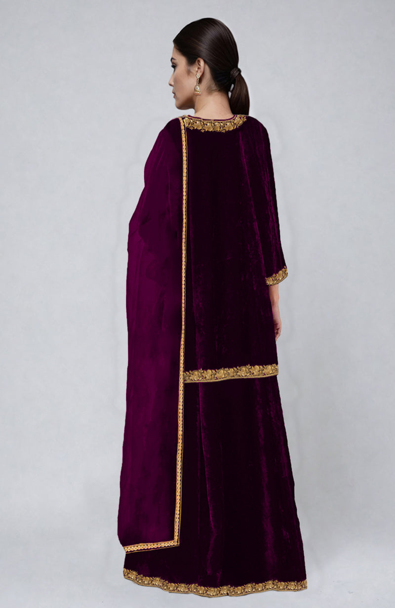 A woman models a peacock pink velvet sharara set with gold Tilla dozi embroidery.