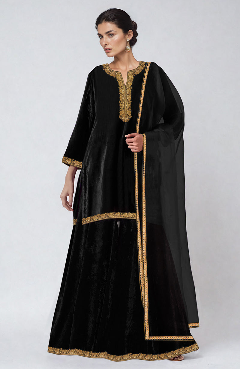 A woman models a black velvet sharara set with gold embroidery.
