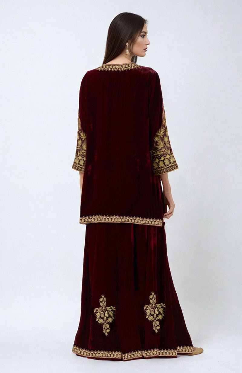 Maroon velvet sharara set with gold Kashmiri tilla embroidery on the neckline, sleeves, and hem.
