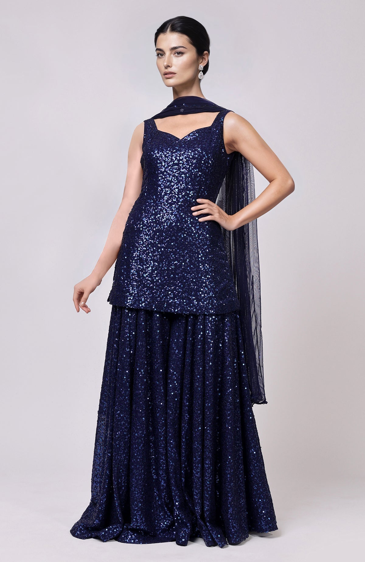 A woman models a sapphire blue sequin embroidered sharara set with a dupatta.