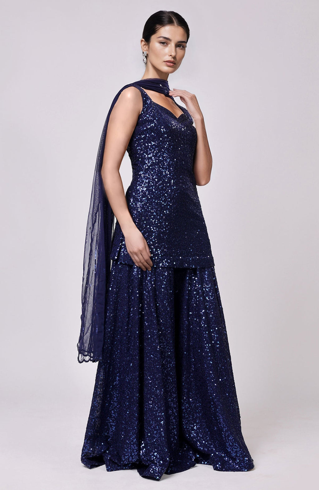 A model wears a sapphire blue sequin embroidered sharara set with a matching dupatta.