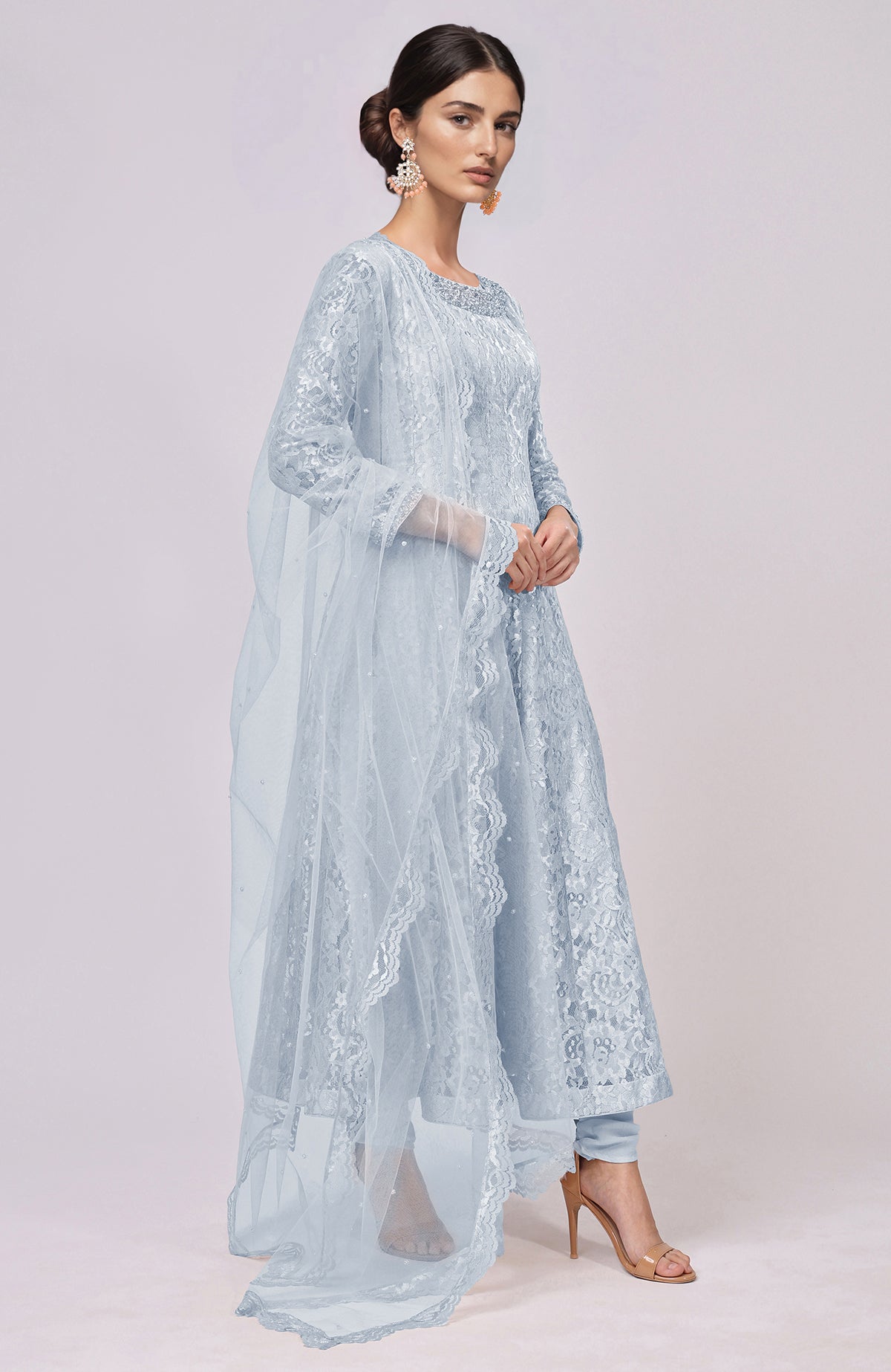 A model wears a light blue lace anarkali set with a matching dupatta and nude heels.