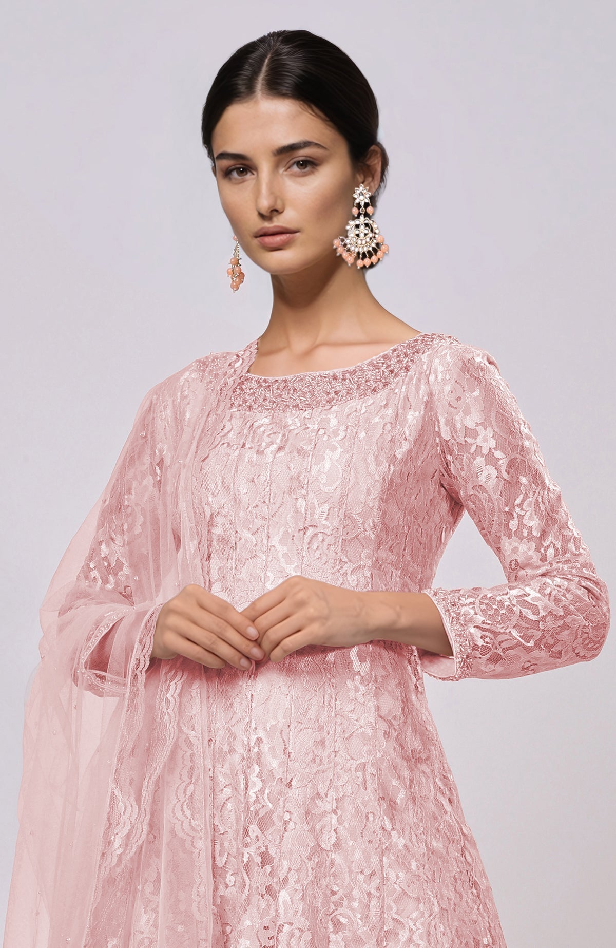 A woman models a pressed rose lace anarkali set with matching earrings.