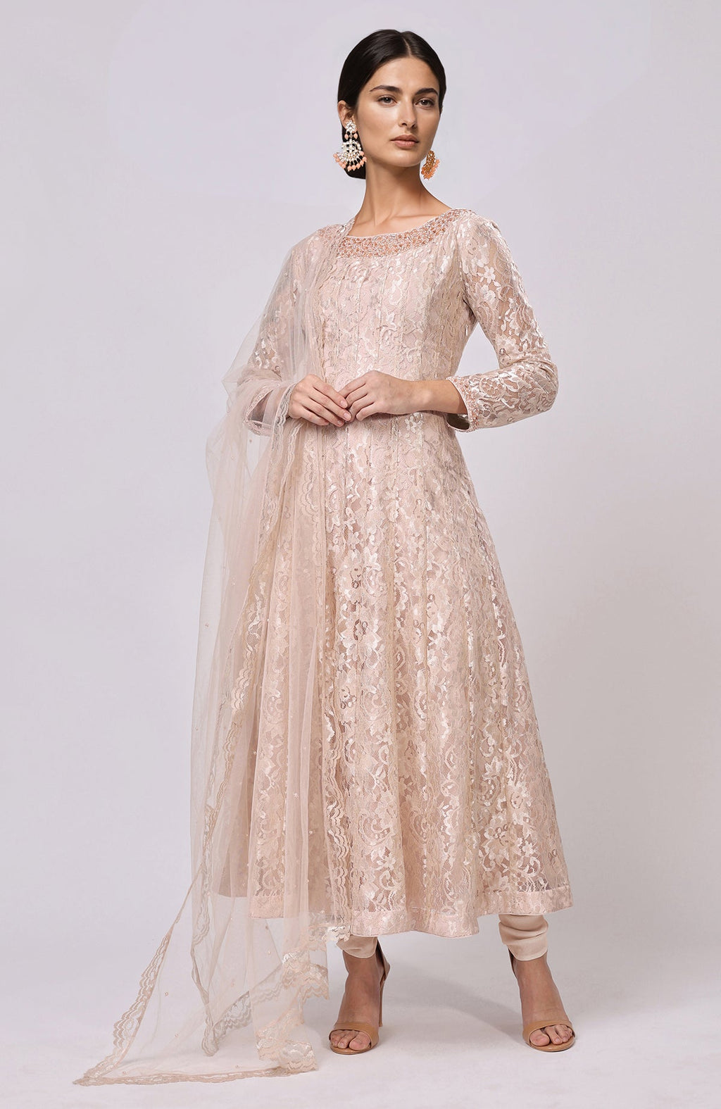 A woman models a champagne lace anarkali set with a matching dupatta and churidar.