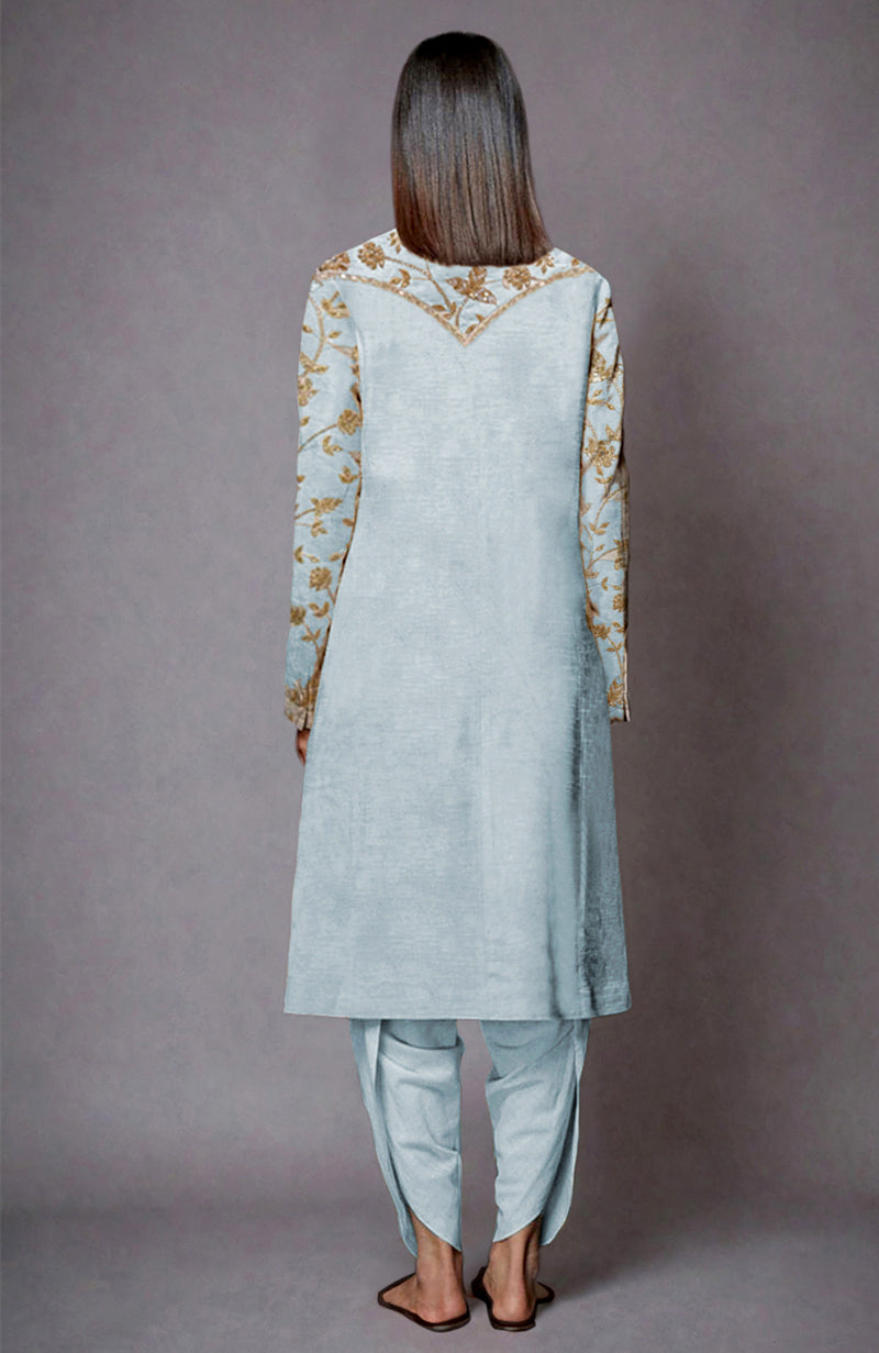 A woman from behind wears an aqua haze jacket with gold and silver embroidery and matching dhoti pants.