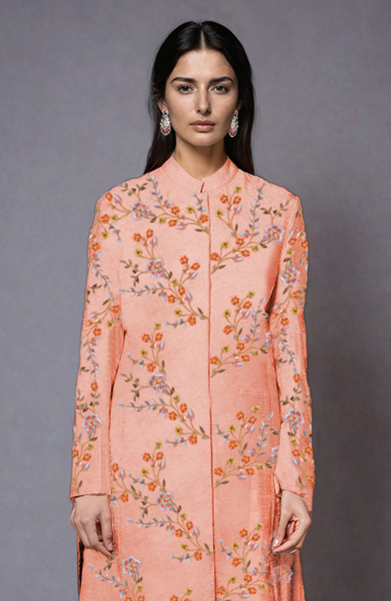 A woman models a salmon jacket with colorful floral embroidery.
