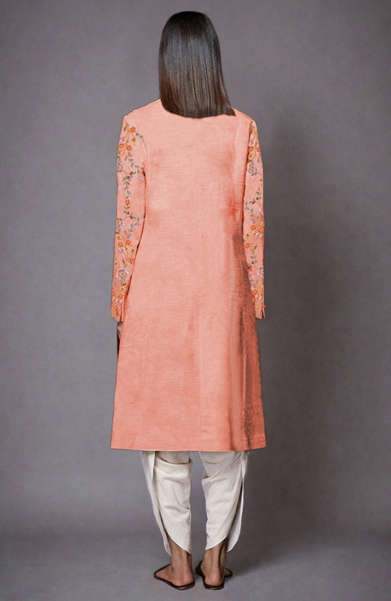 Back view of a model wearing a salmon resham embroidered jacket set with ivory dhoti pants.