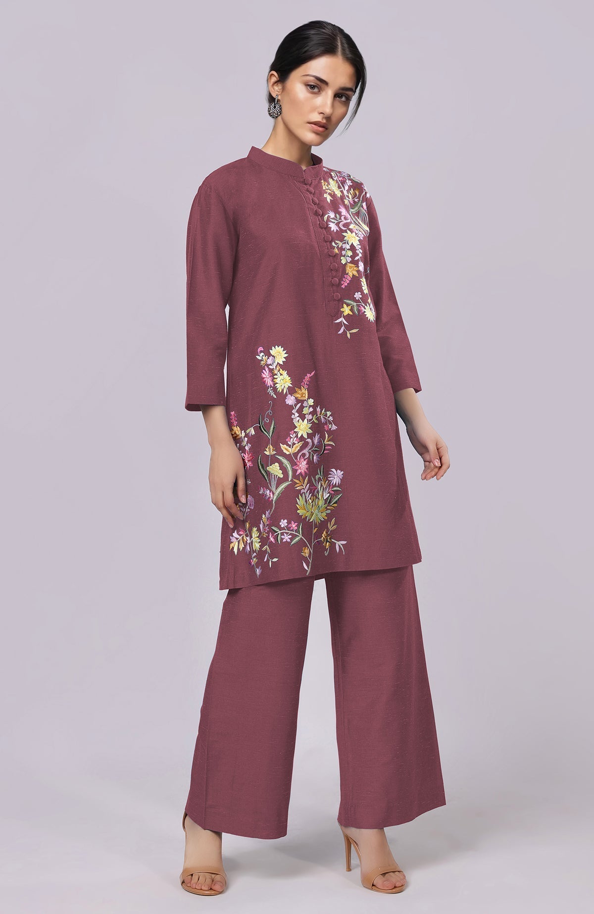 A woman models a maroon co-ord set with colorful floral embroidery.