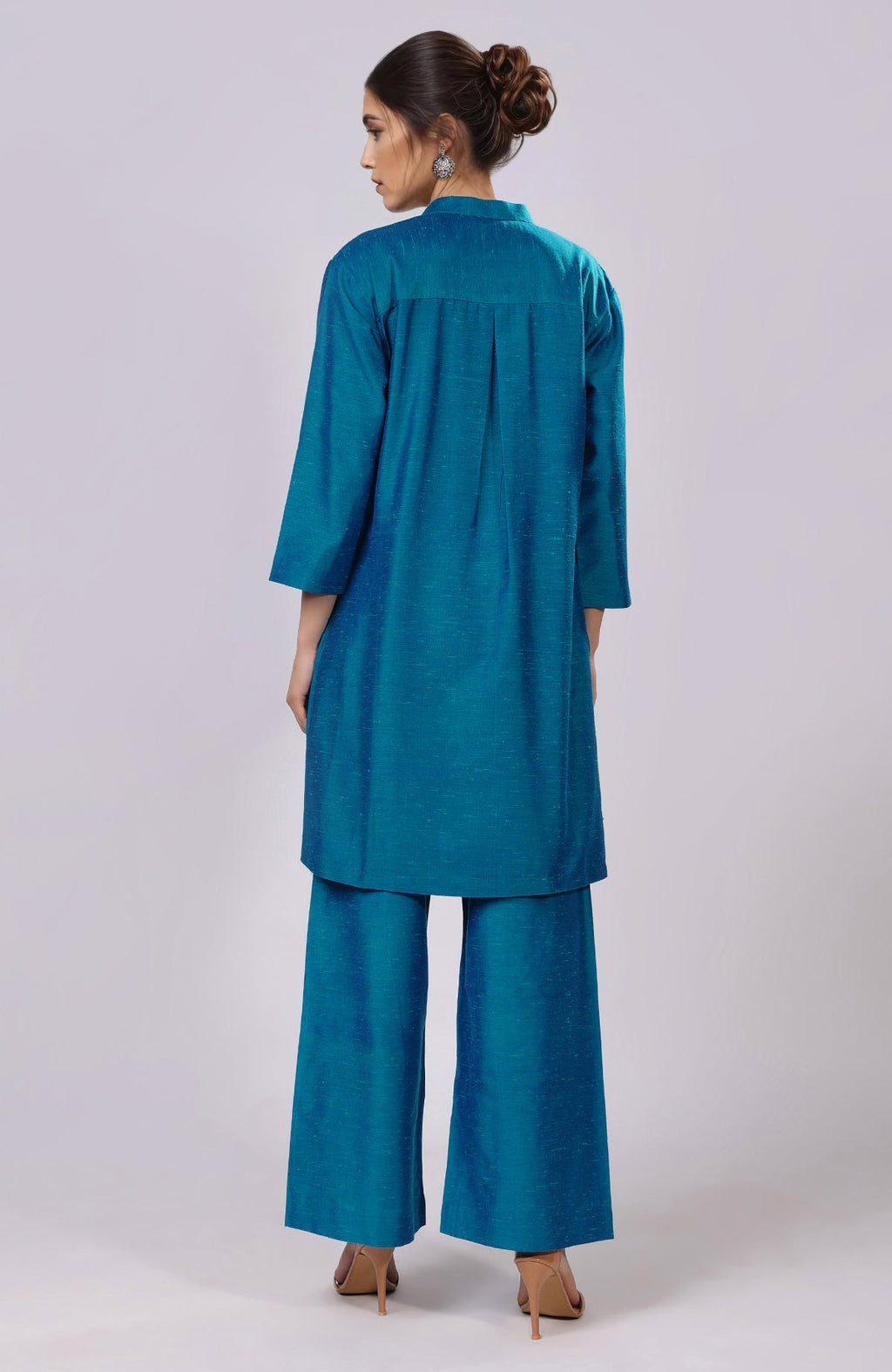 A woman from behind wears a blue Parsi Gara embroidered co-ord set with wide-leg pants.