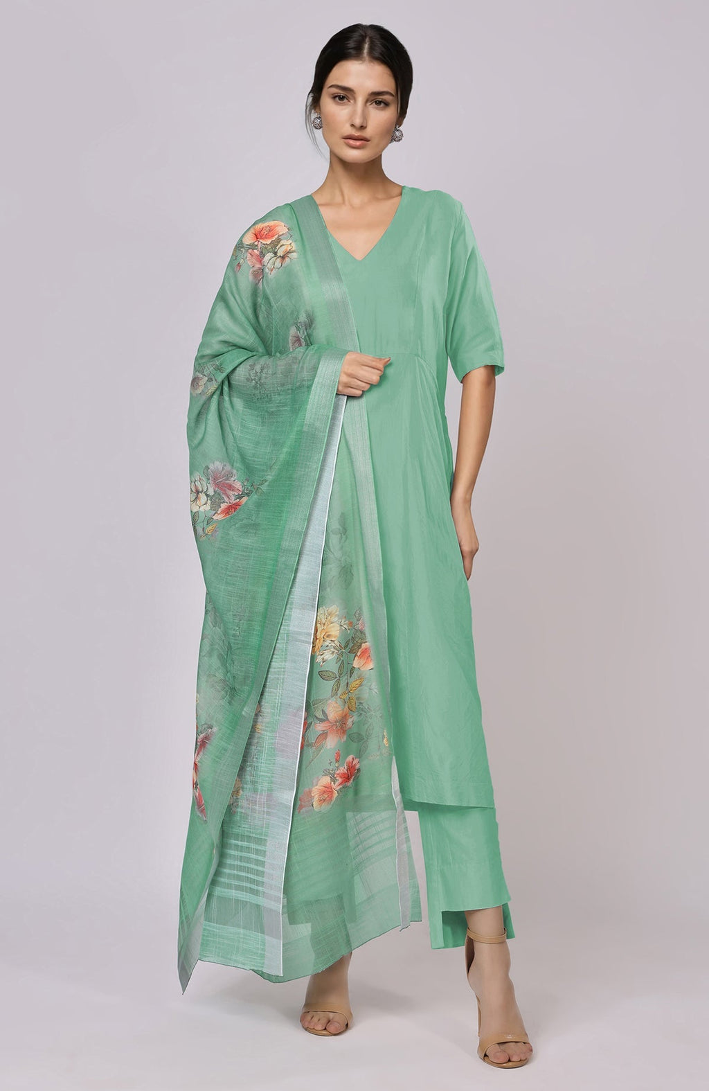 A woman models a dusty jade green floral linen dupatta with a matching suit.