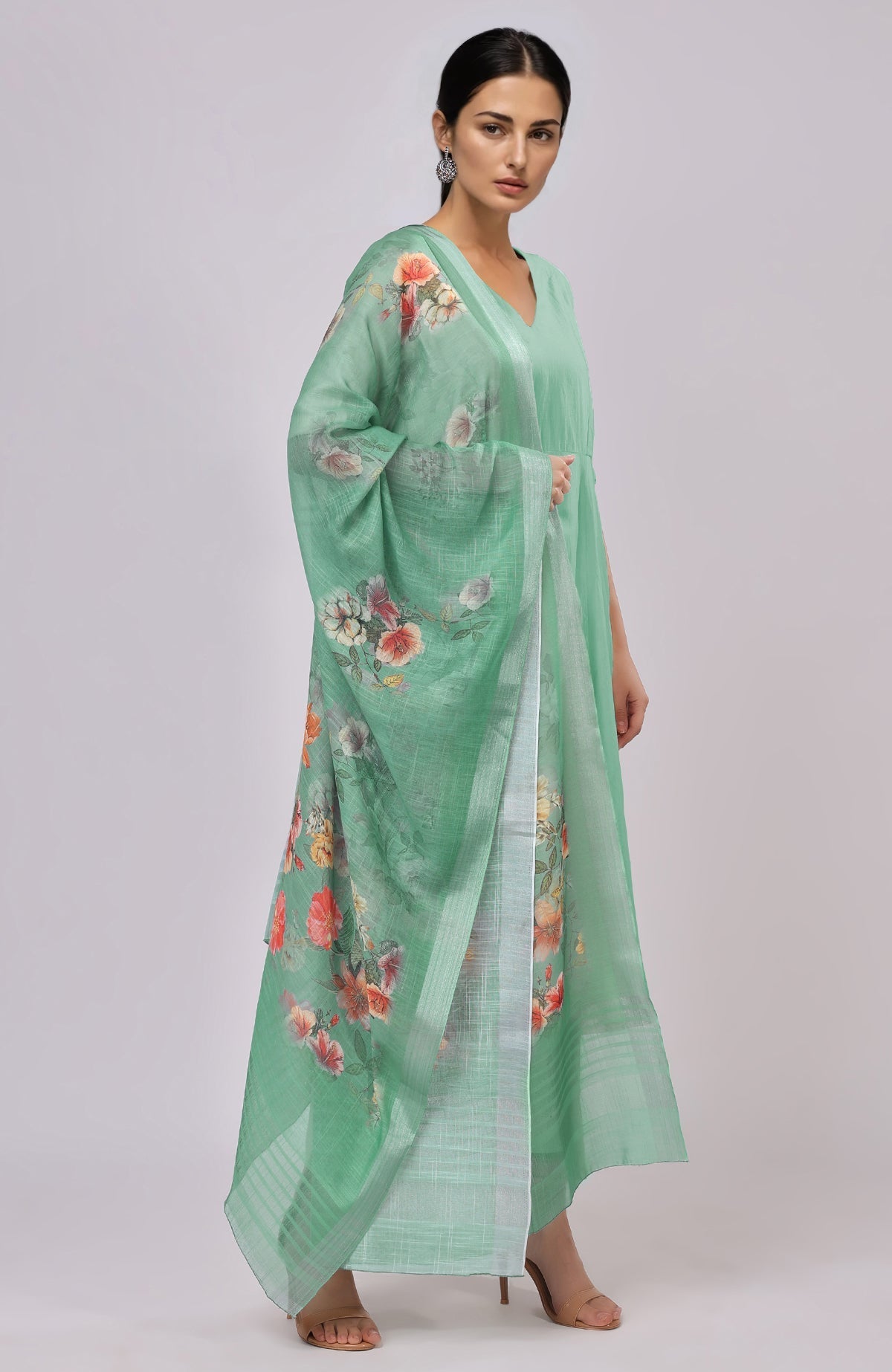 A woman models a dusty jade green floral linen dupatta and matching suit.