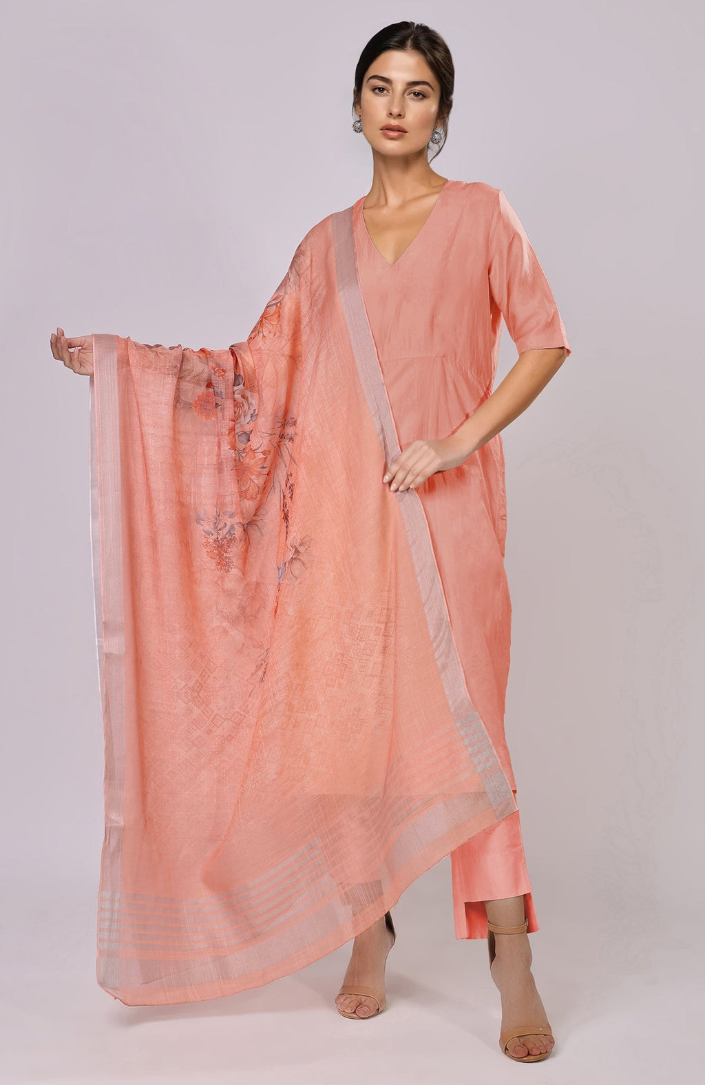 A woman models a peach linen suit with a floral dupatta.