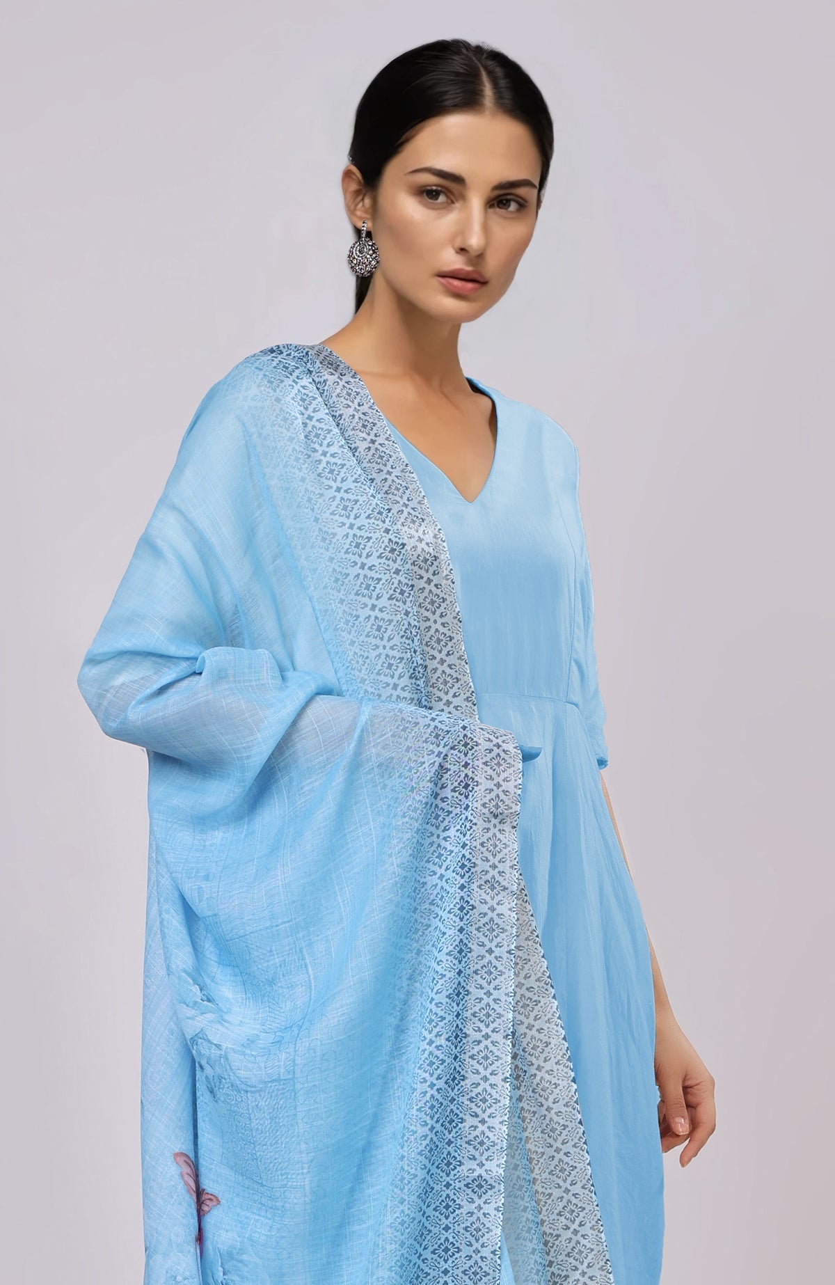A woman models a sky blue linen suit with a floral dupatta.