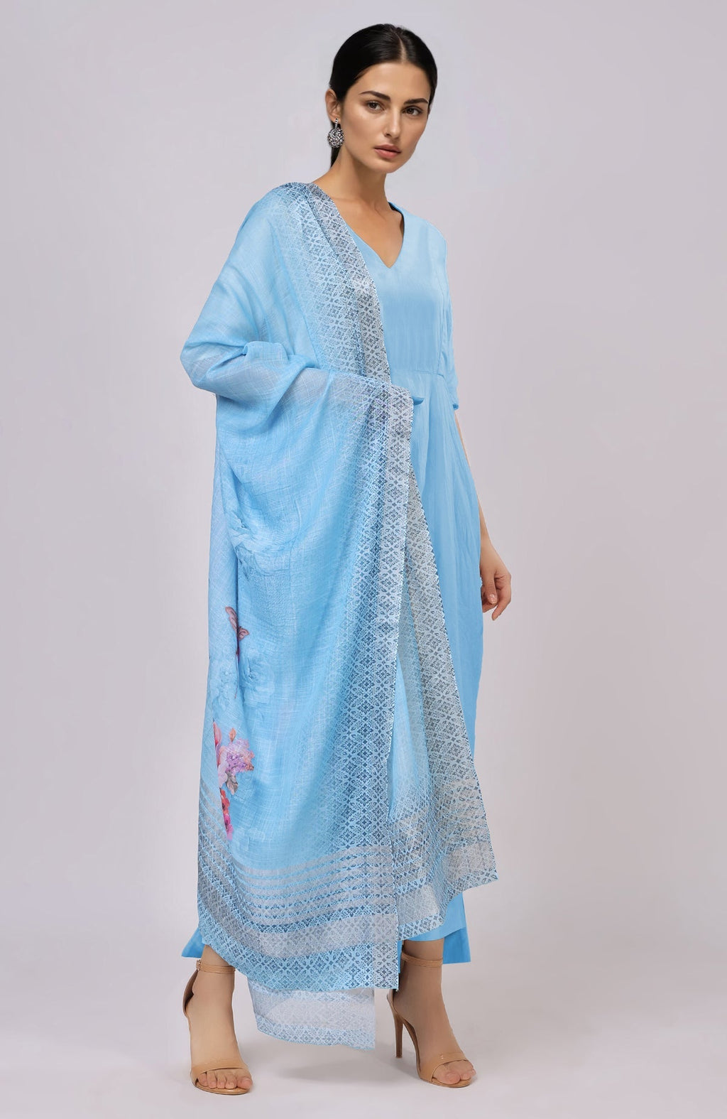 A woman models a sky blue linen suit with a floral dupatta.