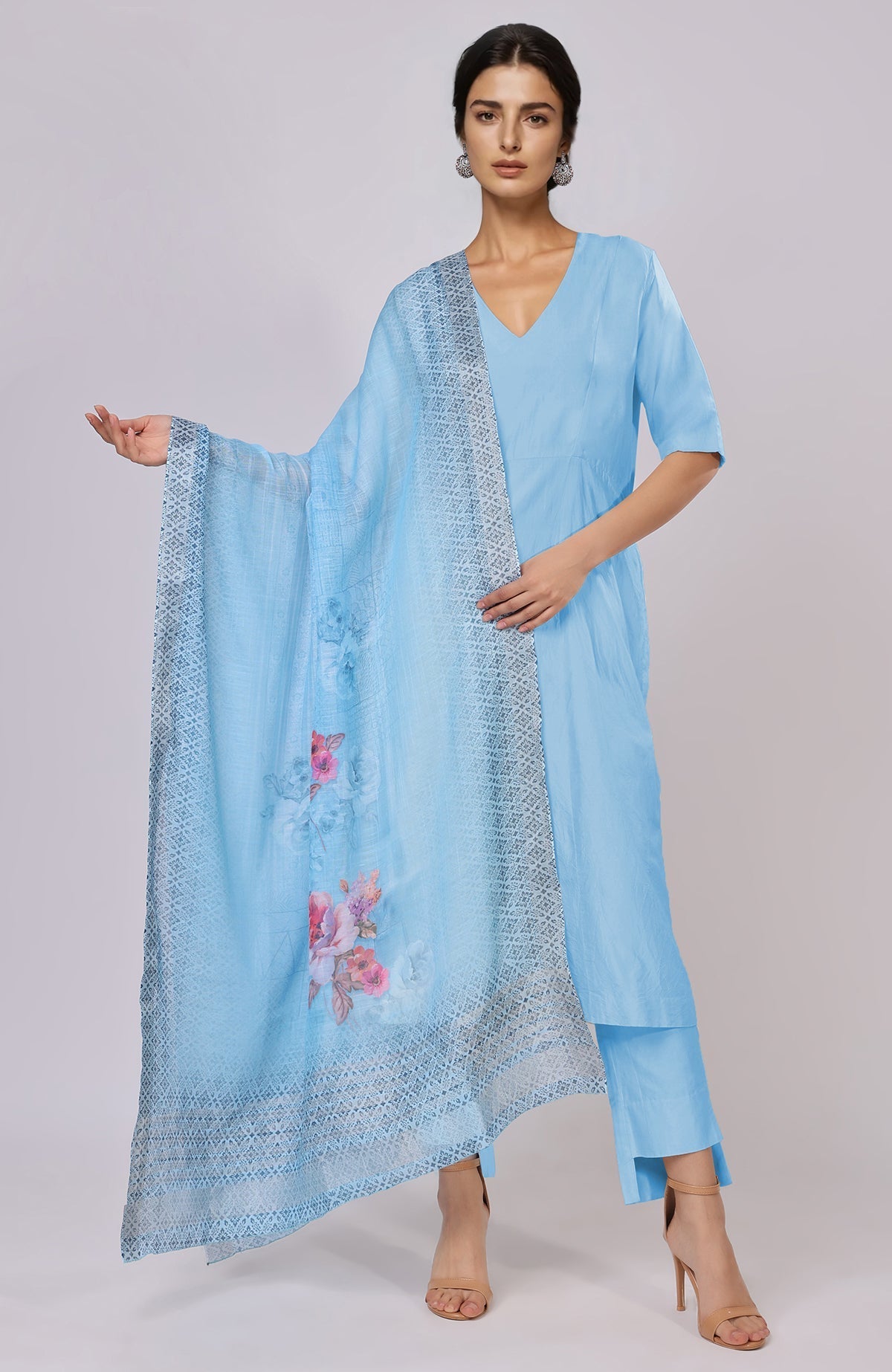 A woman models a sky blue linen suit with a floral dupatta.