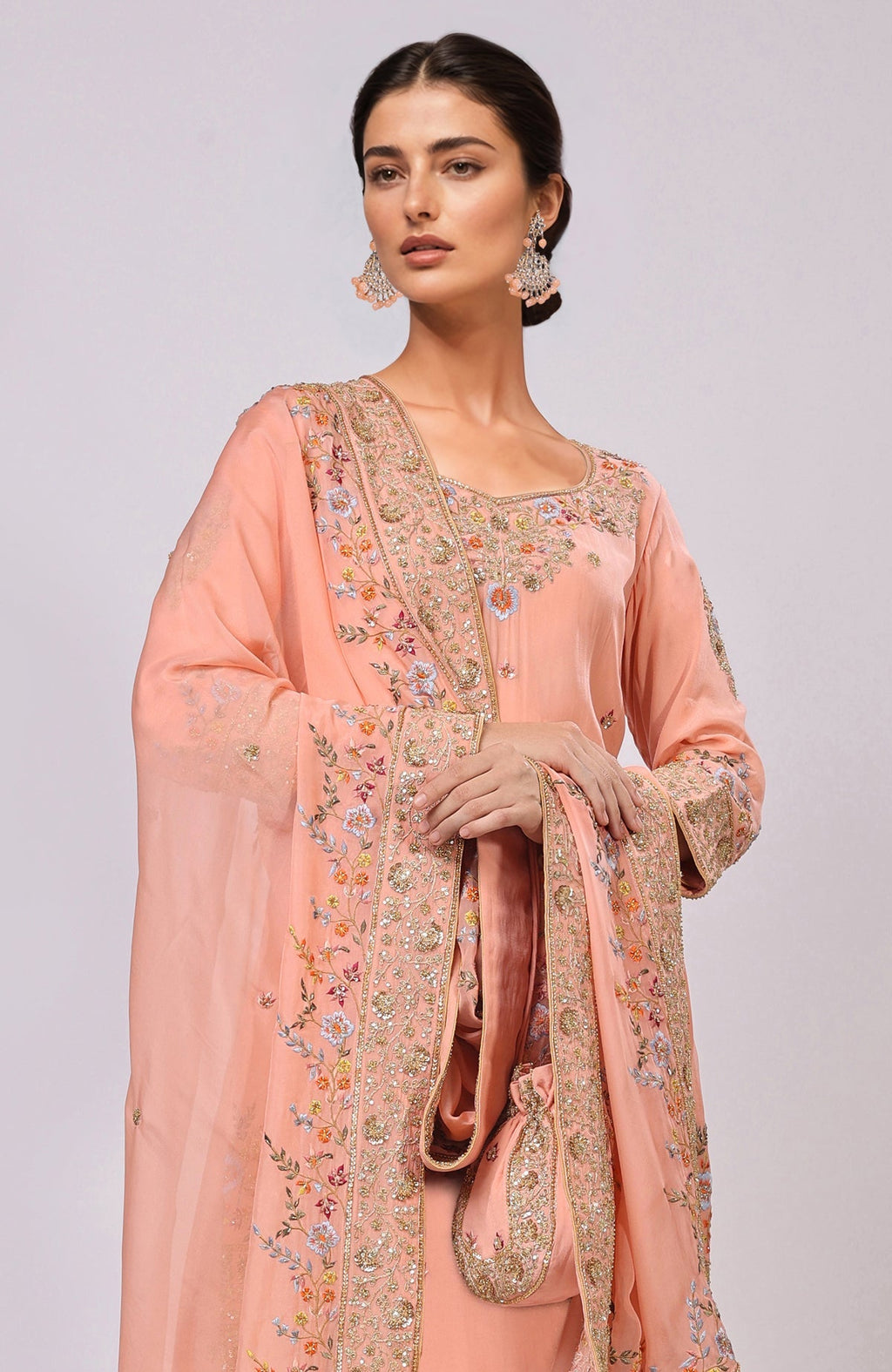 Salmon kurta set with intricate hand embroidery and a matching potli bag.