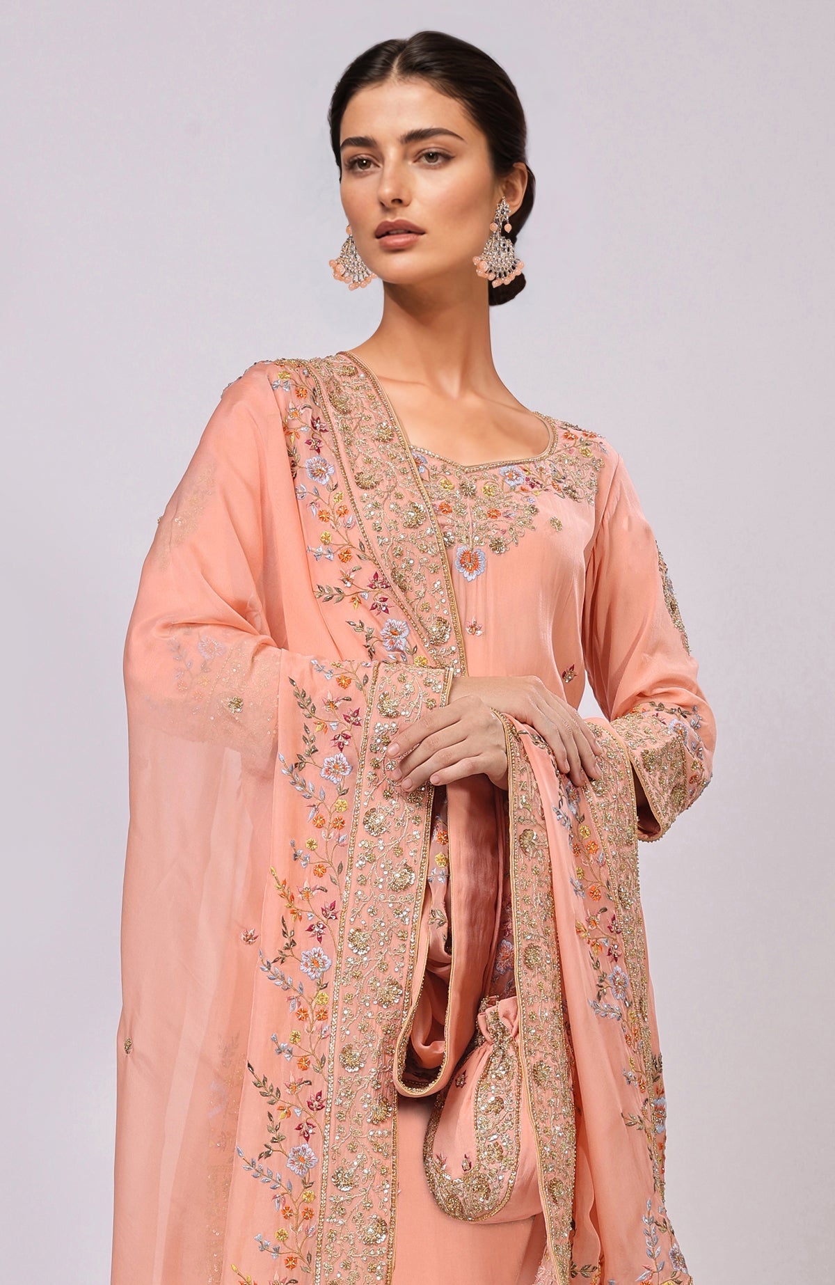 Salmon kurta set with intricate hand embroidery and a matching potli bag.