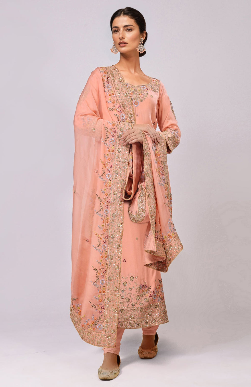A woman models a salmon kurta set with intricate marori and resham embroidery.