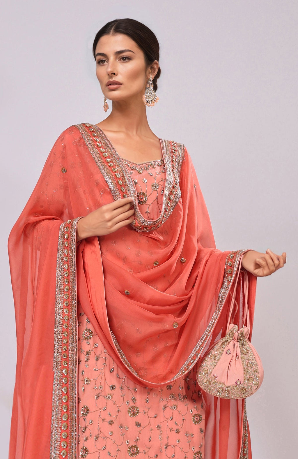 Salmon kurta set with dabka and zardozi embroidery, paired with a matching potli bag.