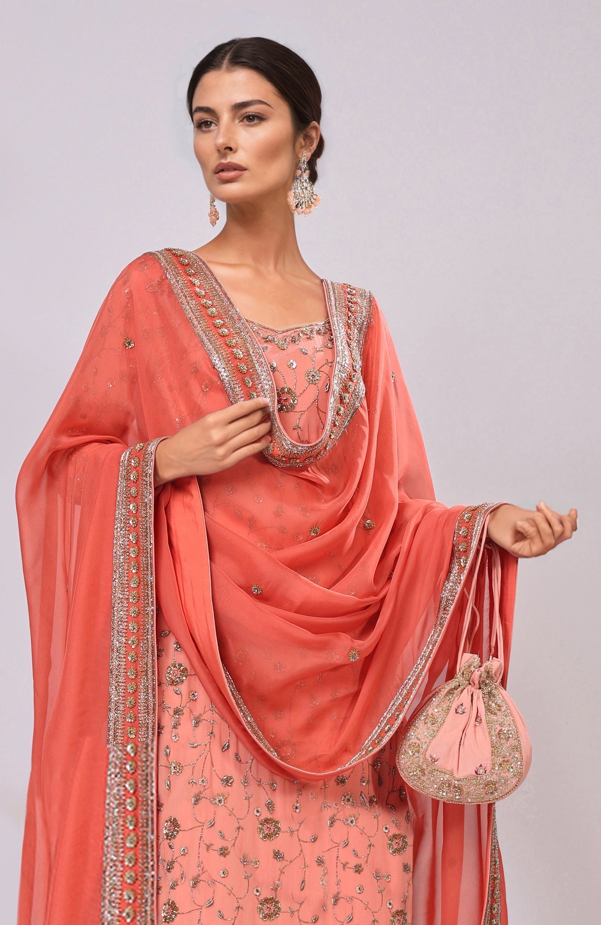 Salmon kurta set with dabka and zardozi embroidery, paired with a matching potli bag.