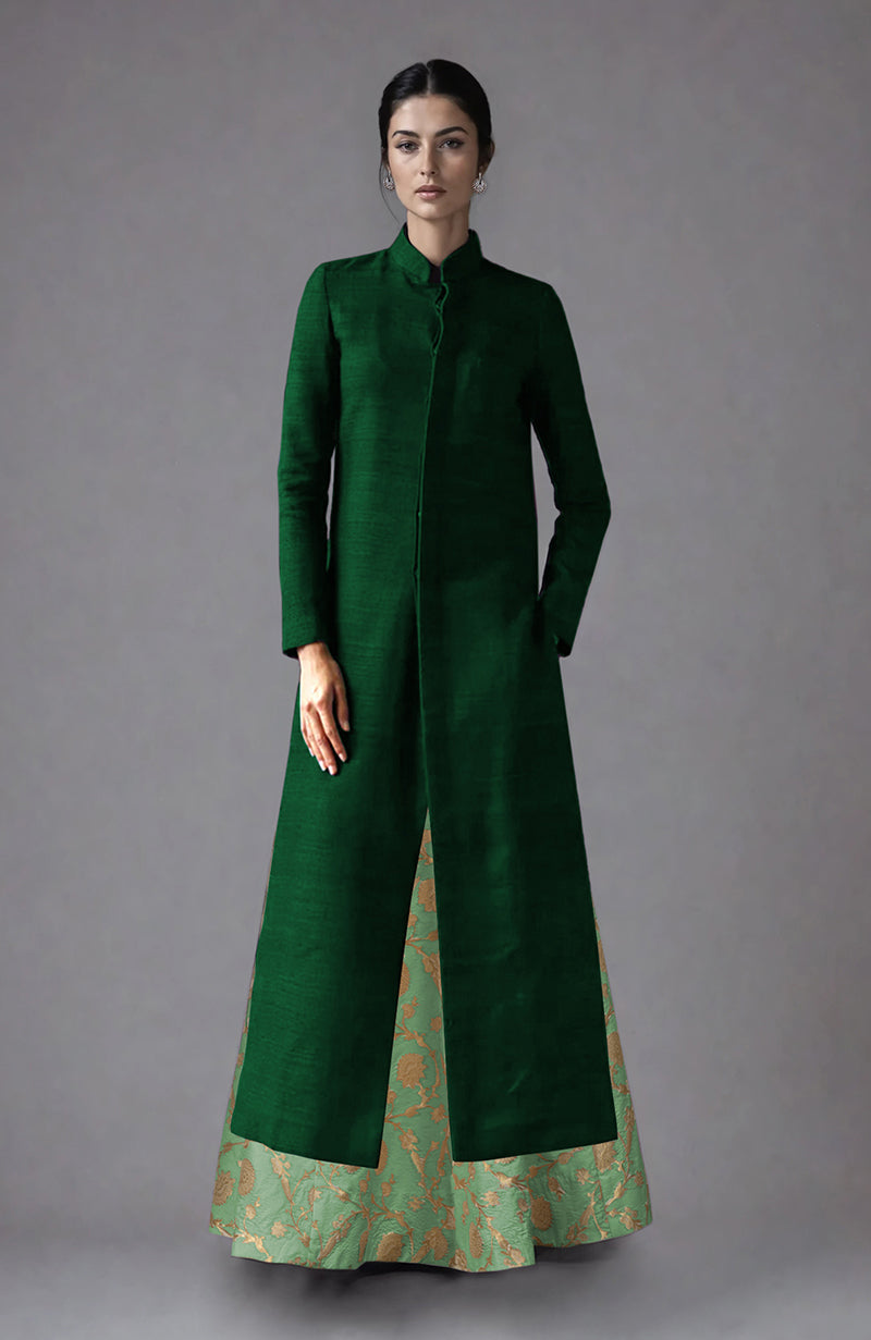 A woman models an open dark green raw silk jacket over a light green brocade skirt.