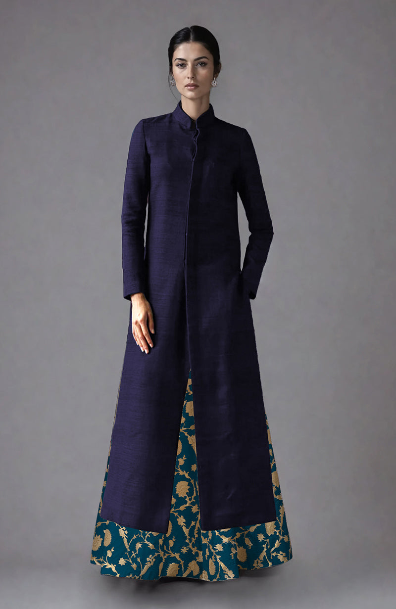 A woman models a navy raw silk jacket with a teal and gold brocade skirt.