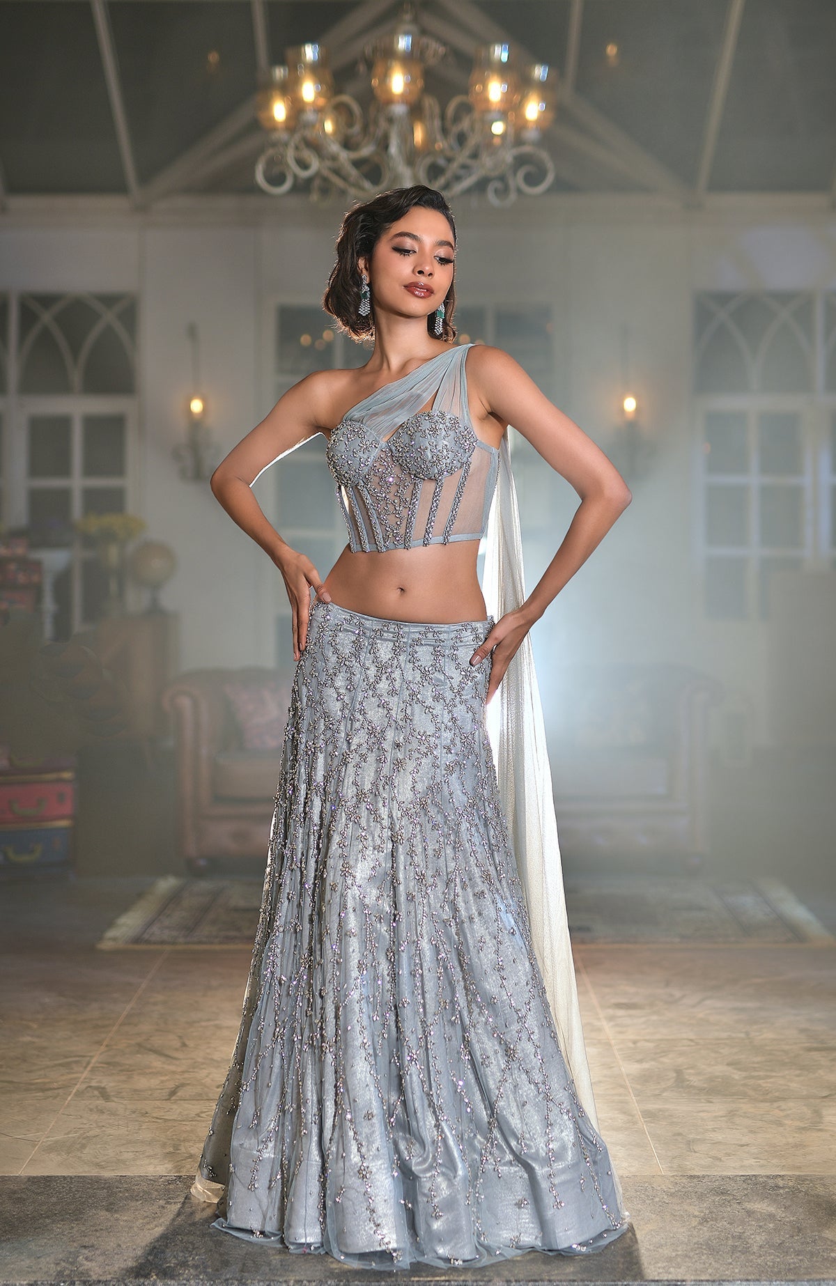 Silver grey corset lehenga set with hand-embroidered silver crystal floral designs and one-shoulder cape.