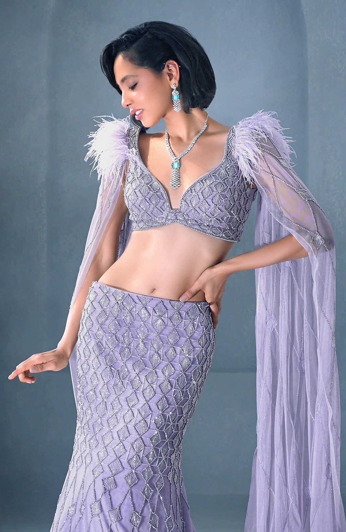 Lilac mermaid lehenga with silver crystal embroidery, feathered shoulders, and tulle cape.