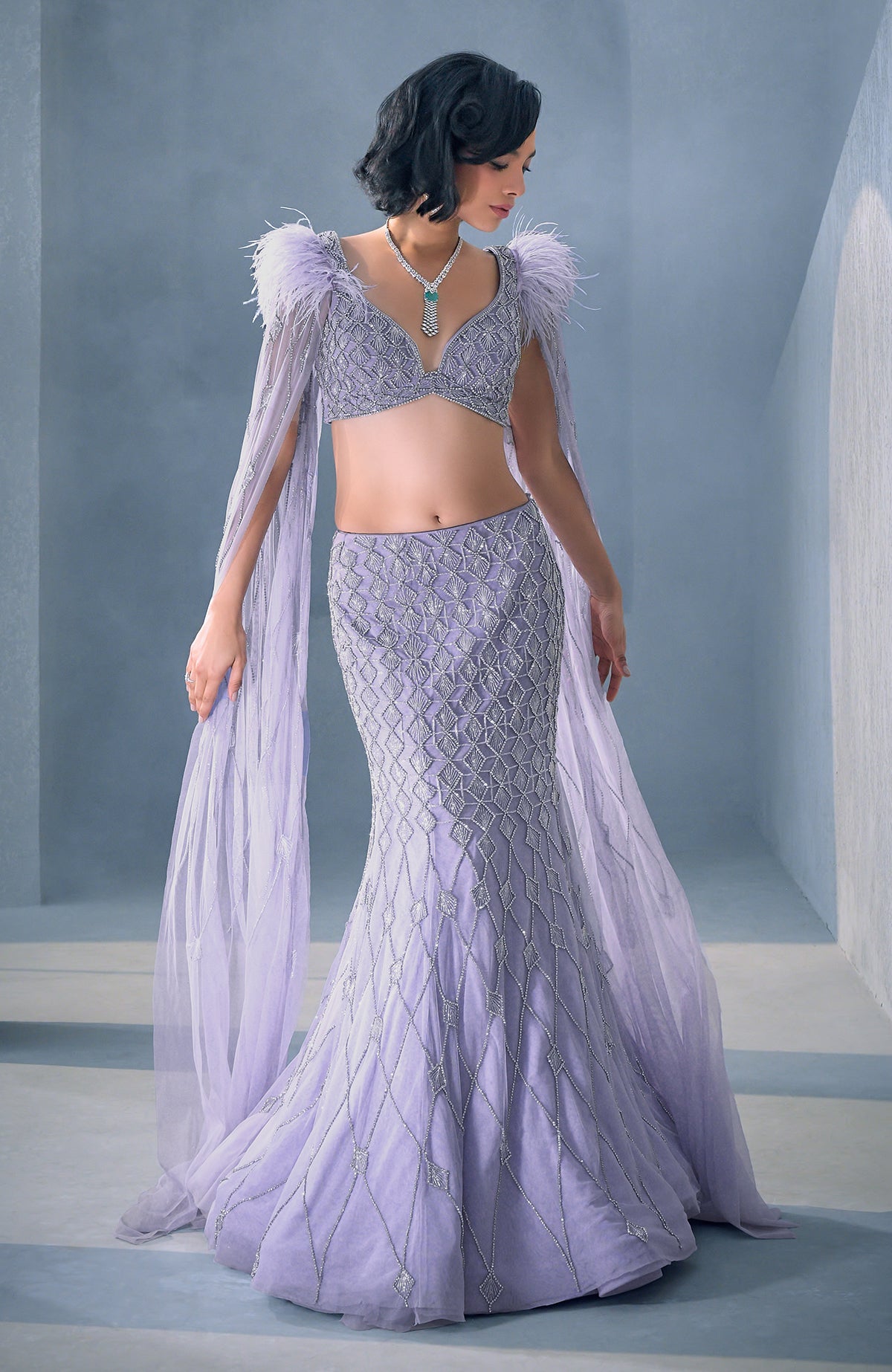 Lilac mermaid lehenga with silver crystal embroidery, feathered shoulders, and tulle cape.