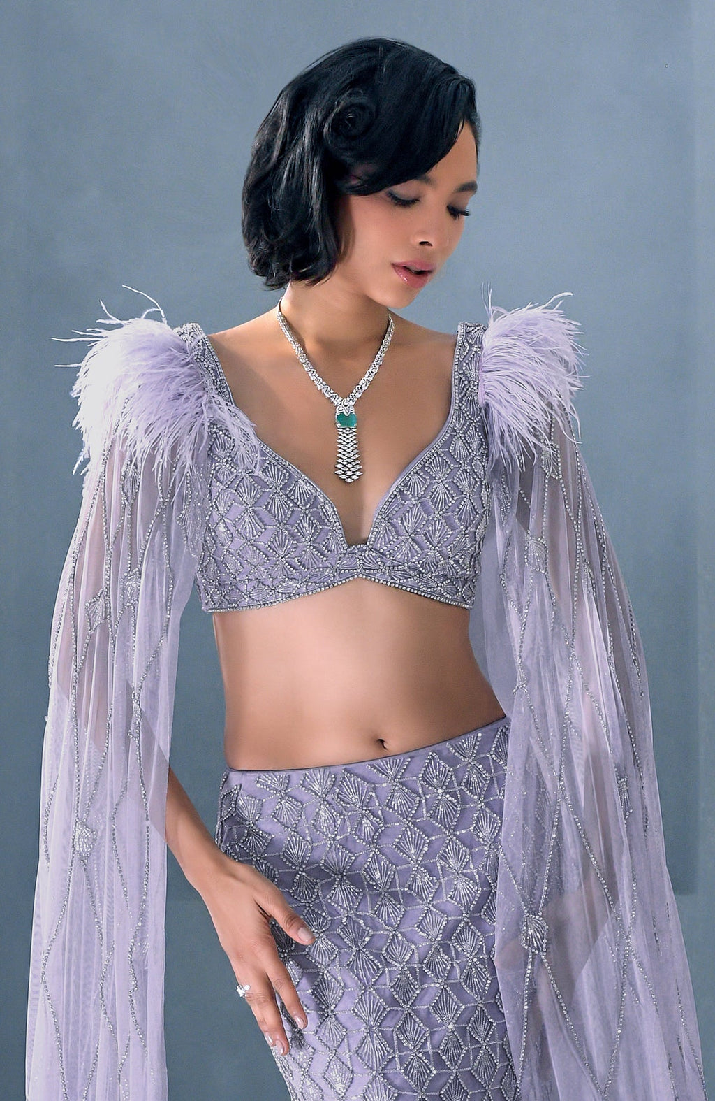 Lilac mermaid lehenga with silver crystal embroidery, feathered shoulders, and tulle cape.