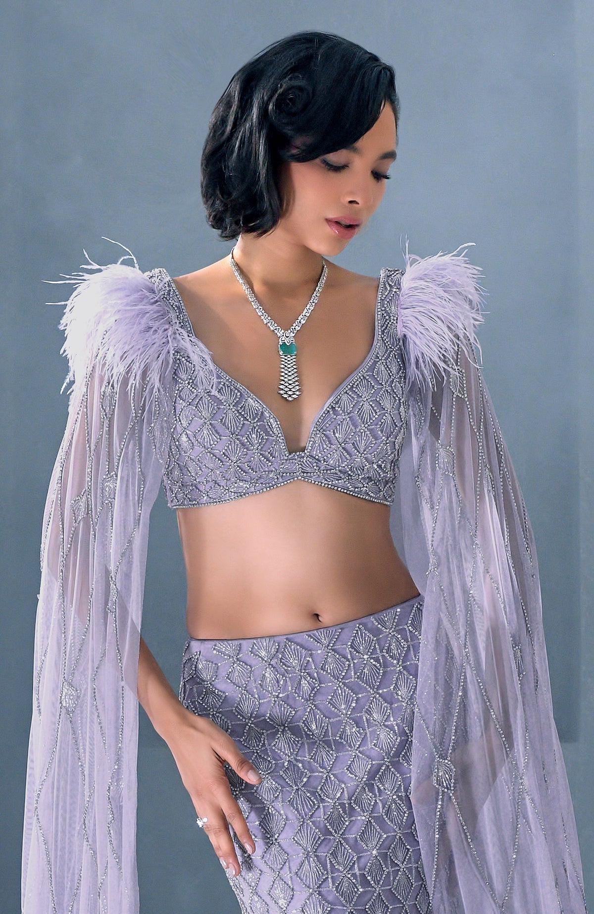 Lilac mermaid lehenga with silver crystal embroidery, feathered shoulders, and tulle cape.
