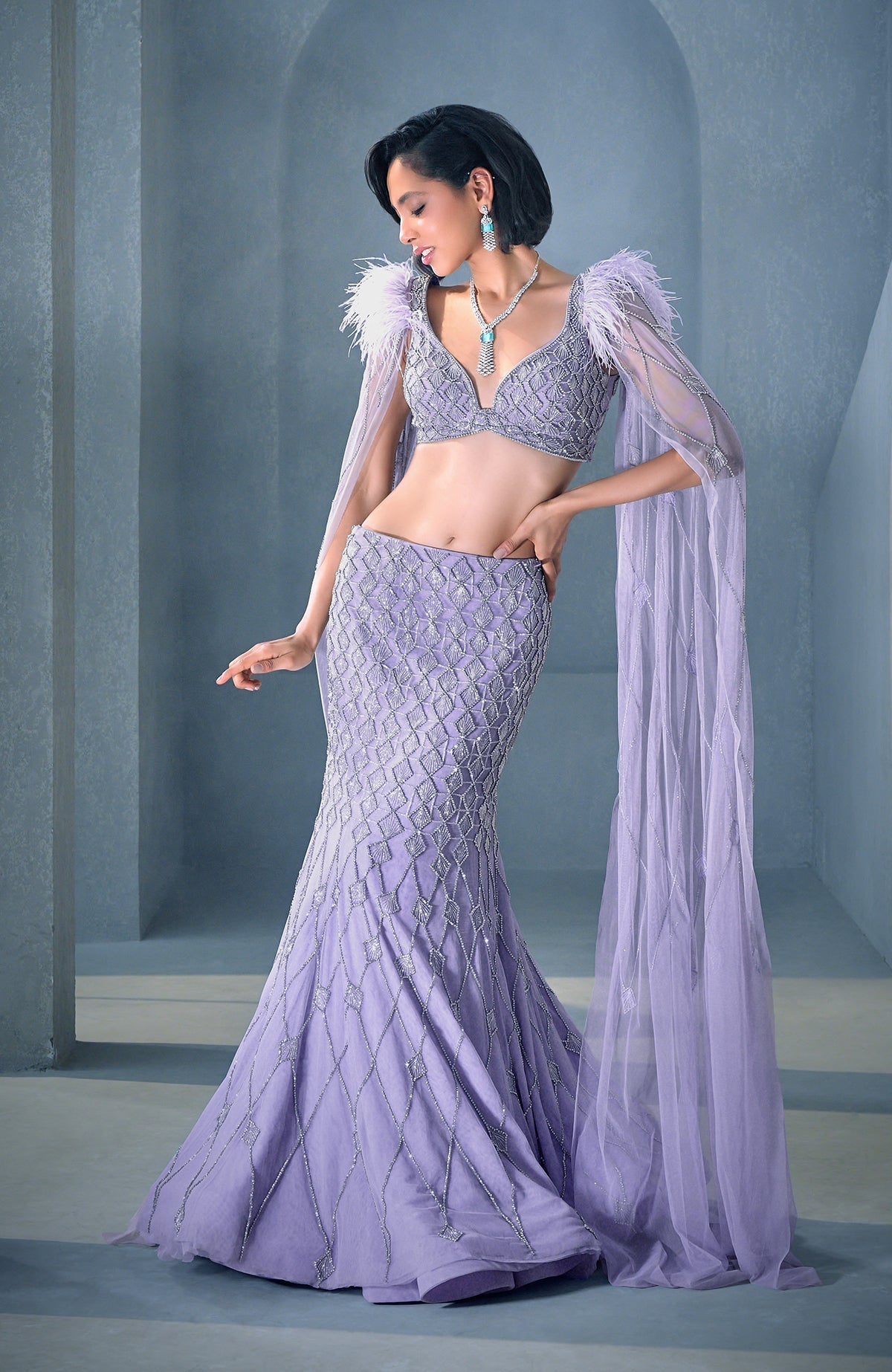 Lilac mermaid lehenga with silver crystal embroidery, feathered shoulders, and tulle cape.