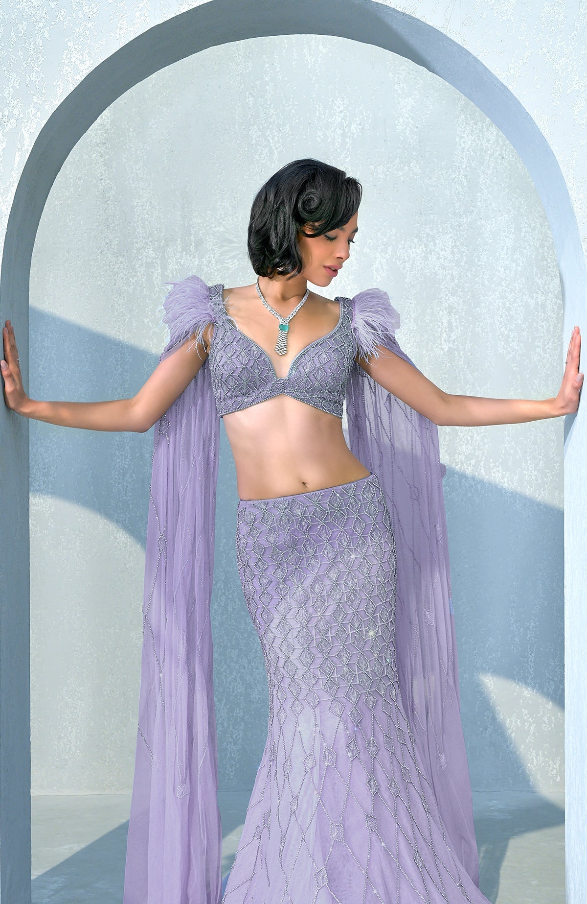 Lilac mermaid lehenga with silver crystal embroidery, feathered shoulders, and tulle cape.