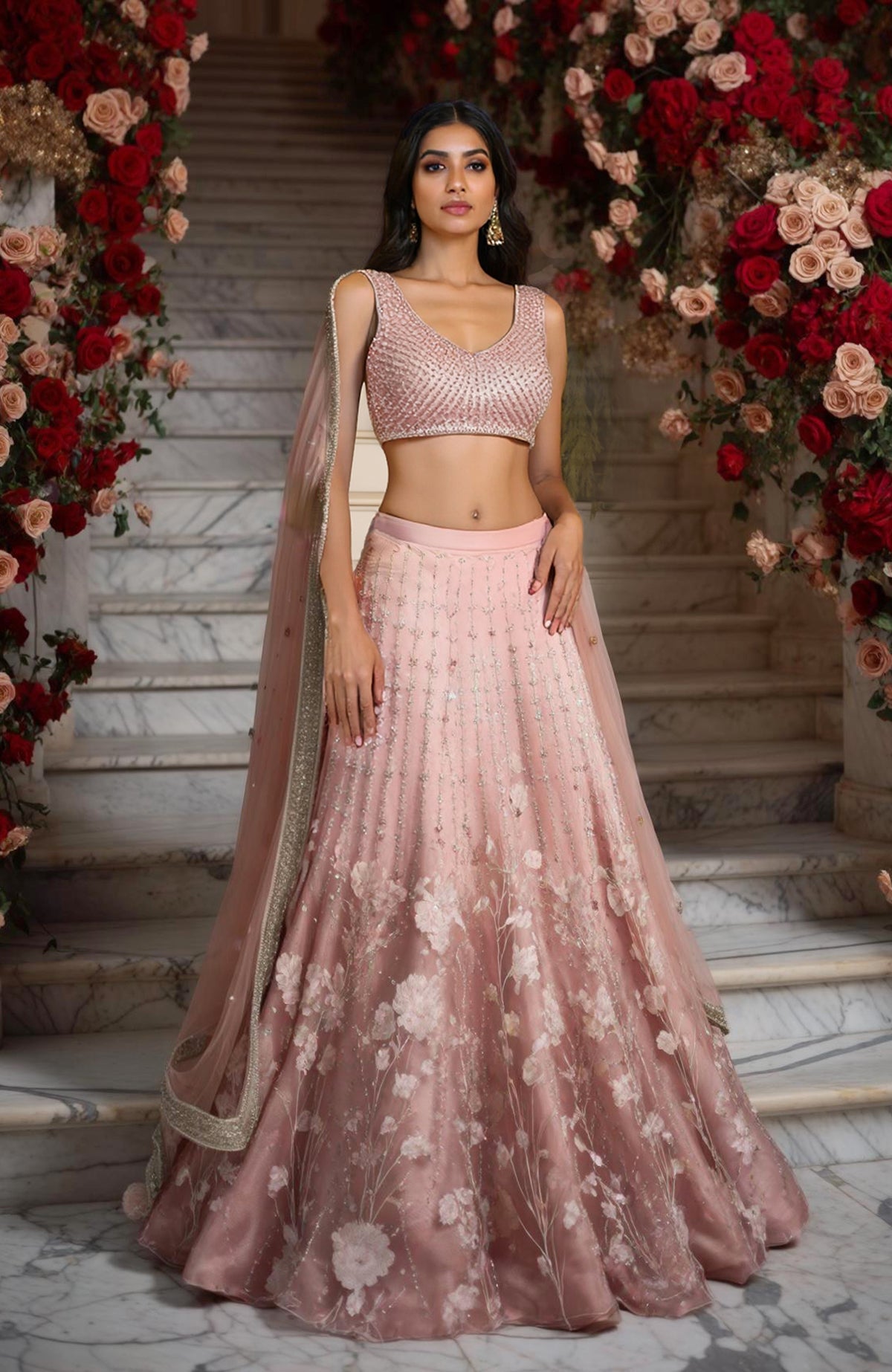 Blush pink lehenga set with sleeveless embellished blouse, floral embroidered skirt, and sheer dupatta.