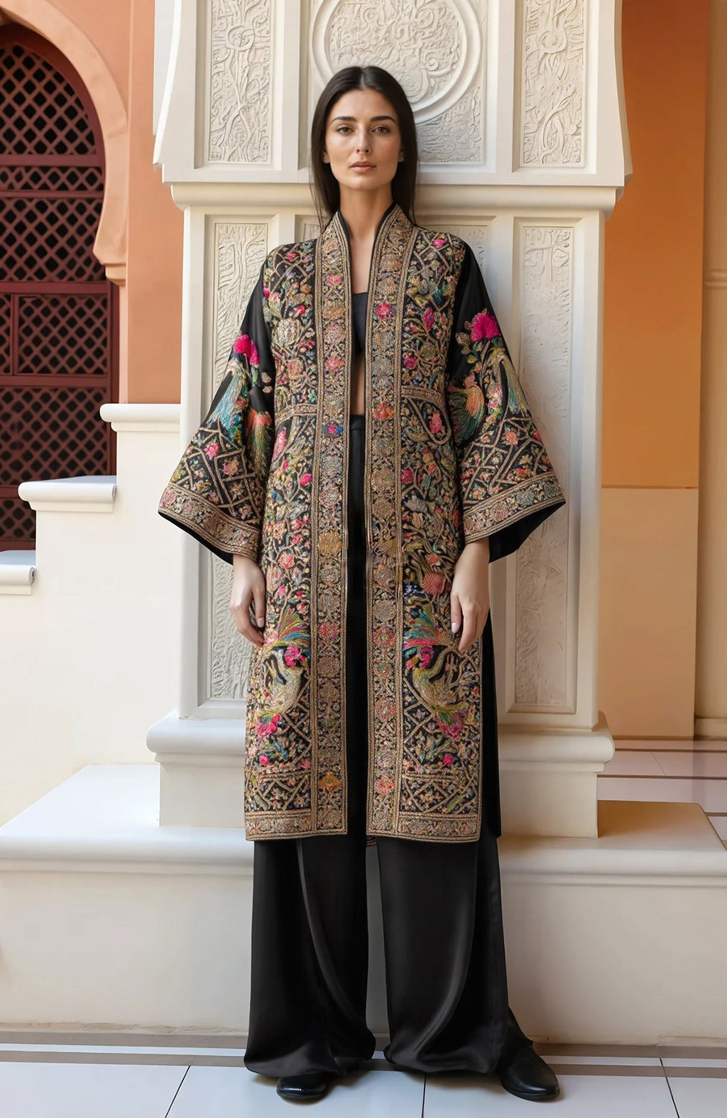 Black kimono jacket with gold, pink, green, and blue floral and bird embroidery and wide sleeves.