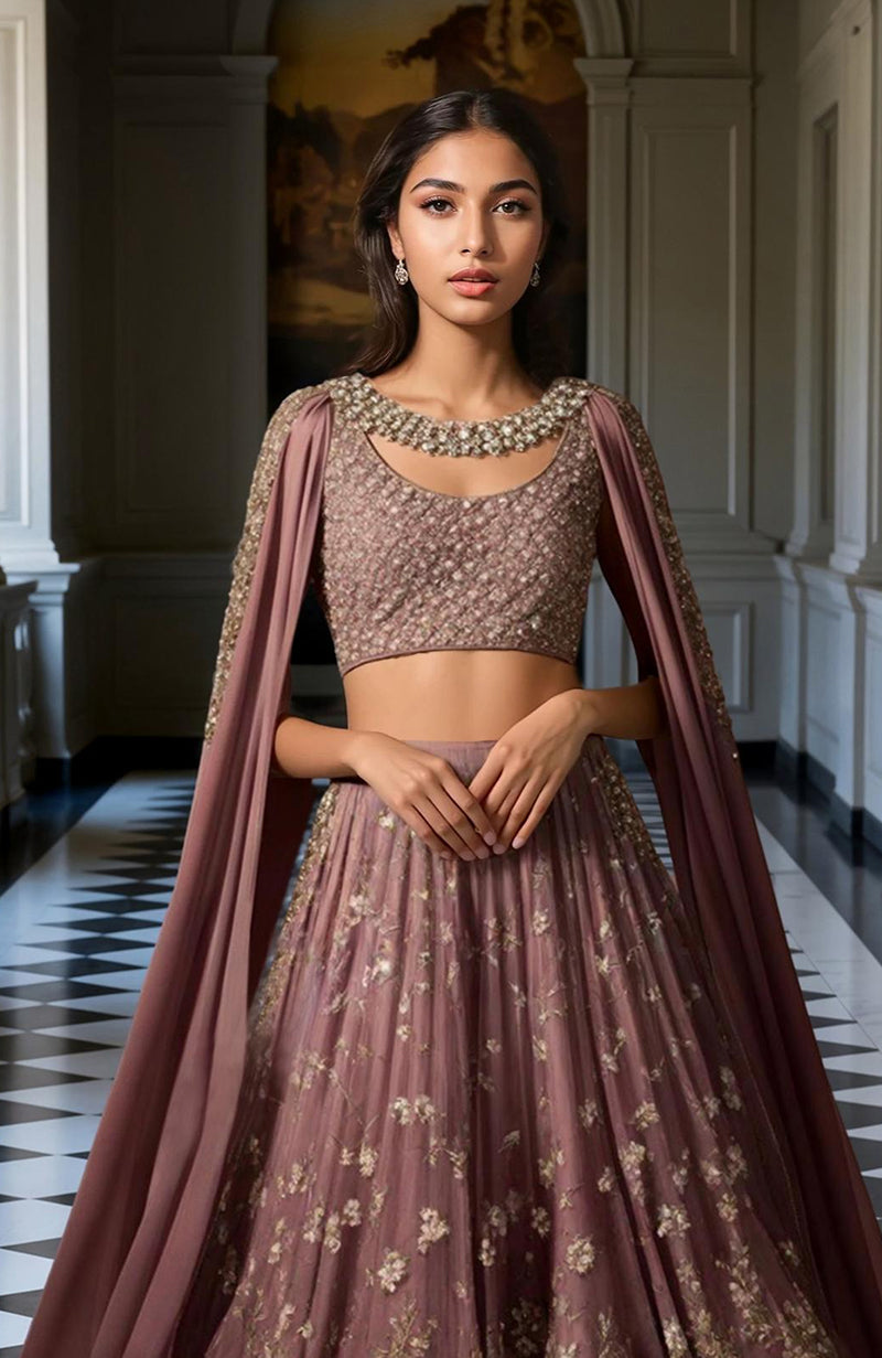 Deep mauve lehenga set with gold floral embroidery, sleeveless blouse, and flowing cape.