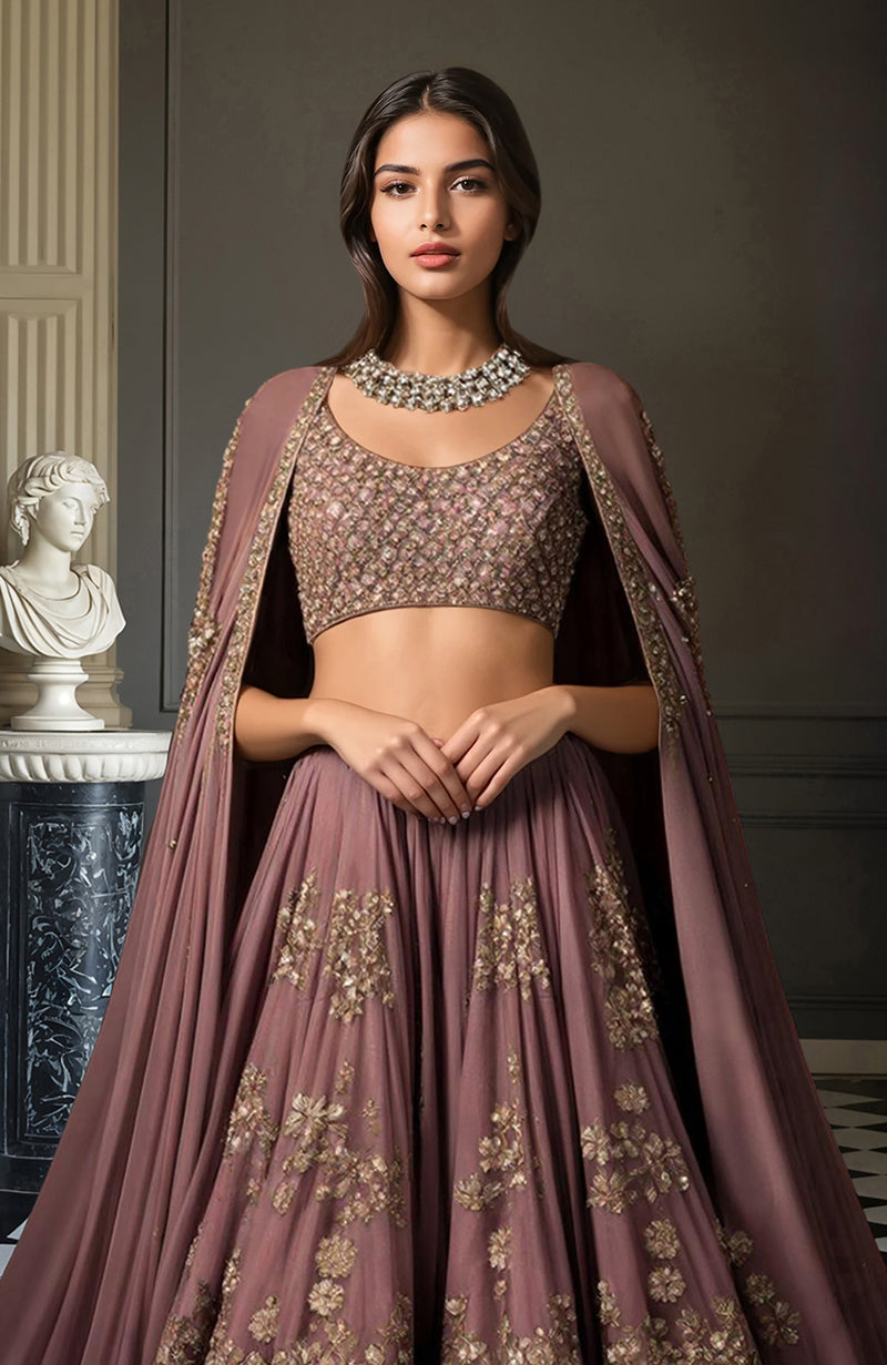 Deep mauve lehenga set with gold floral embroidery, sleeveless blouse, and flowing cape.