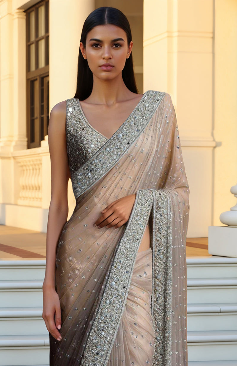 Champagne beige saree with silver sequin and bead embroidery paired with sleeveless blouse.