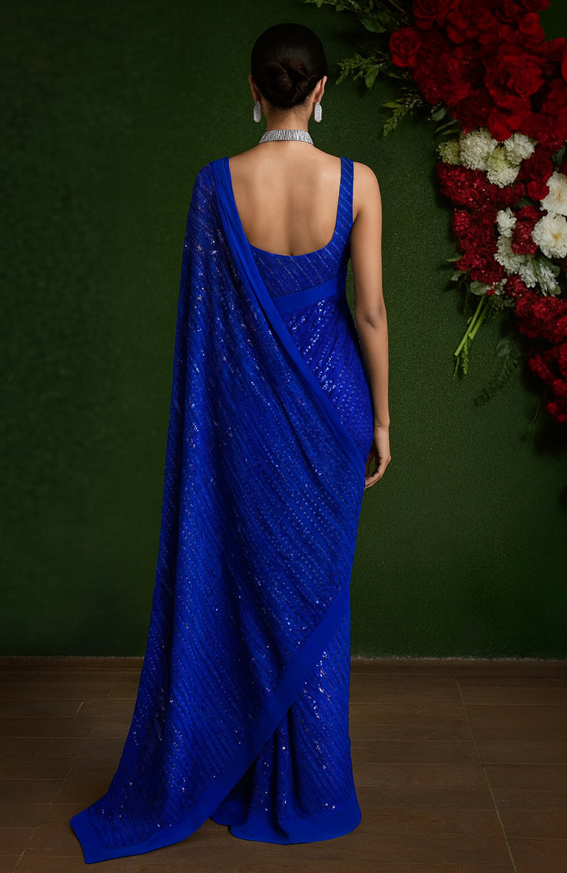 Rich blue saree with diagonal sequin embroidery and sleeveless scoop neck blouse.
