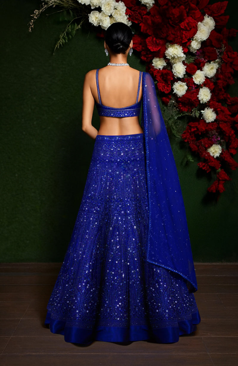 Midnight blue lehenga set with sequin embroidery, scoop-neck blouse, and sheer dupatta draped over shoulder