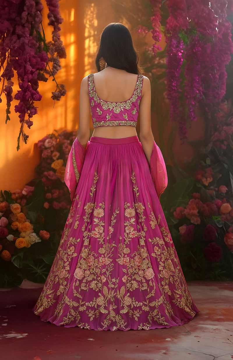 Fuchsia lehenga set with gold floral embroidery, sleeveless blouse, and sheer dupatta with sequins.