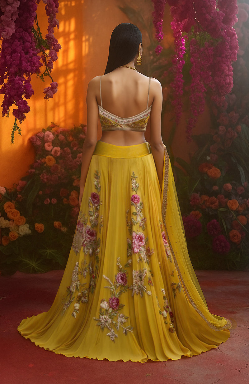 Golden marigold lehenga with pink and ivory floral embroidery, paired with a matching blouse and sheer dupatta.