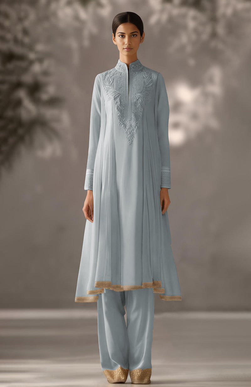 Soft ivory kurta set with floral embroidery, pleated drape design, and tapered gold-embellished trousers.