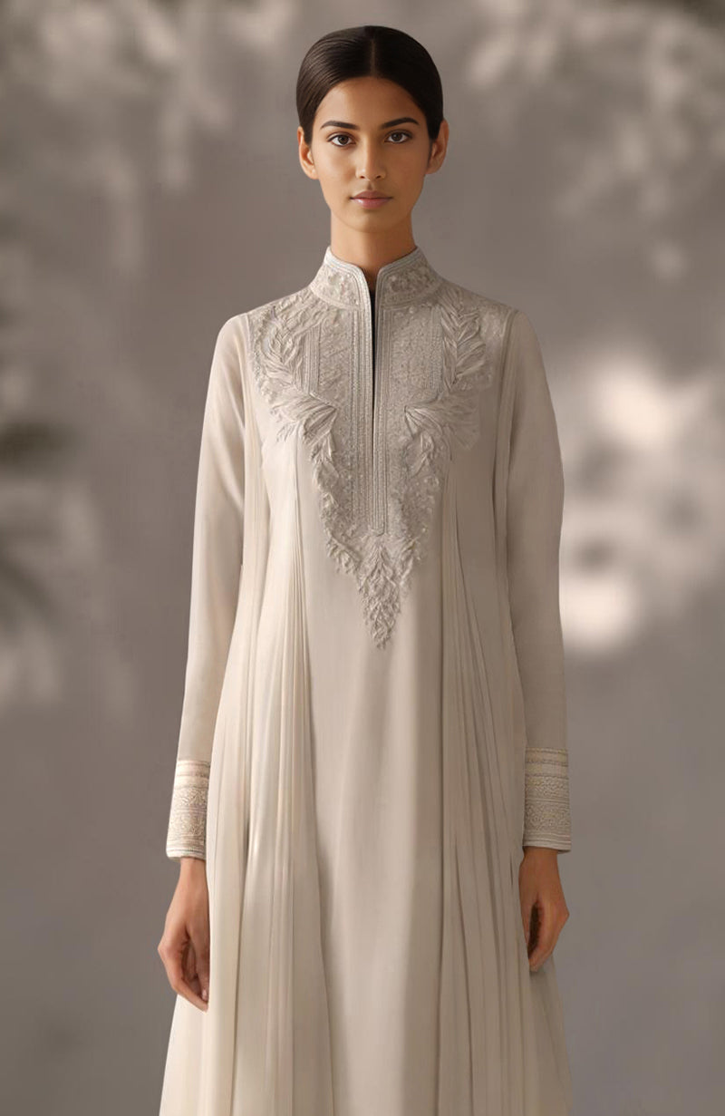 Soft ivory kurta set with floral embroidery, pleated drape detail, and gold-embellished trousers.