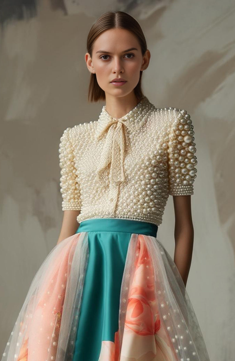 Teal A-line skirt with floral print and sheer overlay paired with pearl-embroidered blouse with bow.