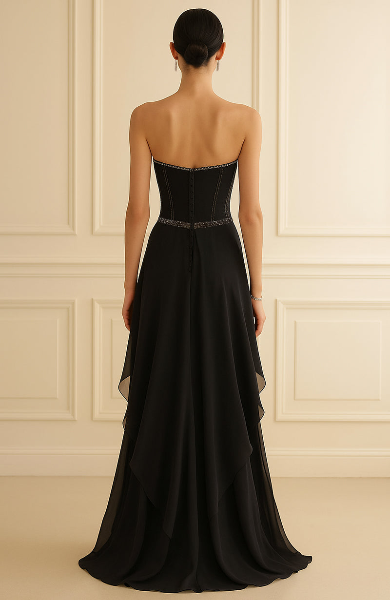 Strapless black evening gown with beaded corset bodice and layered flowing chiffon skirt.