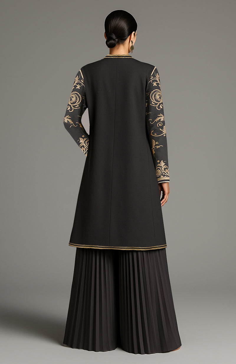 Black longline jacket with antique gold floral embroidery, gold bralette, and black pleated pants.