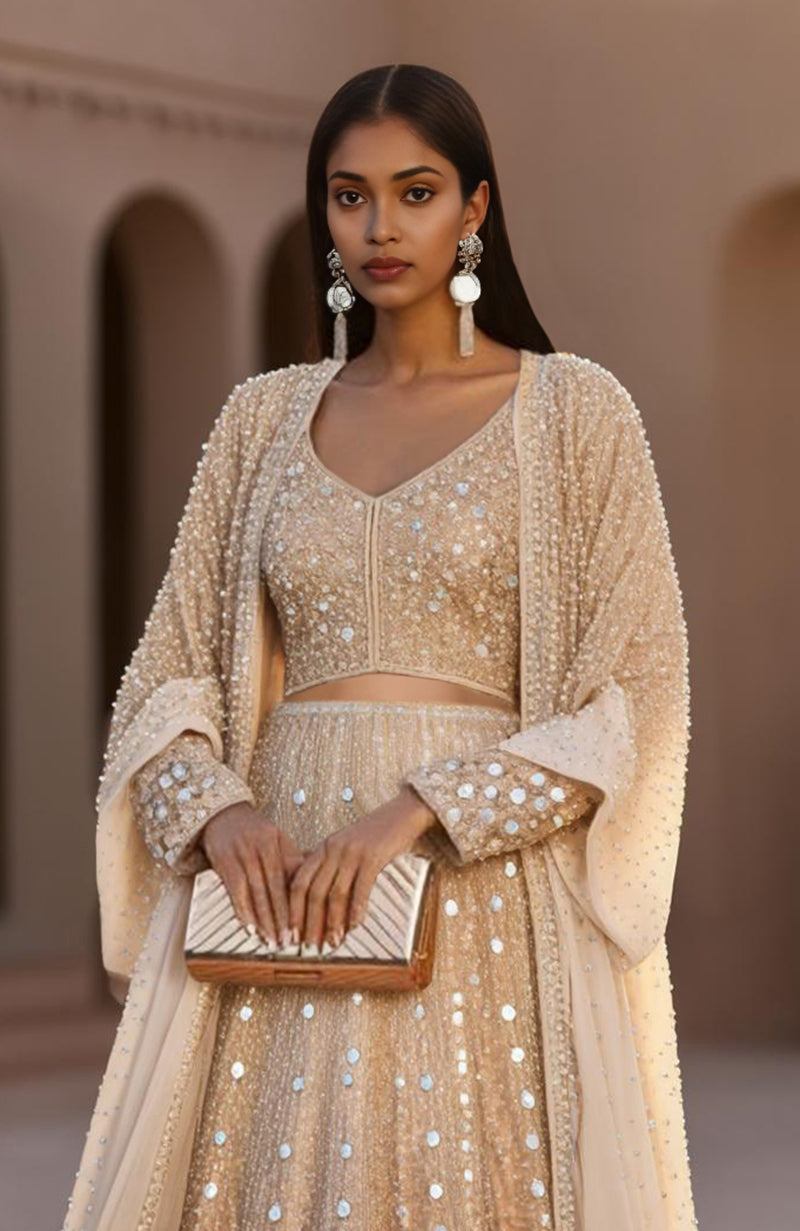 Champagne-colored lehenga set with hand-embroidered mirrors, sequins, and sheer net cape.