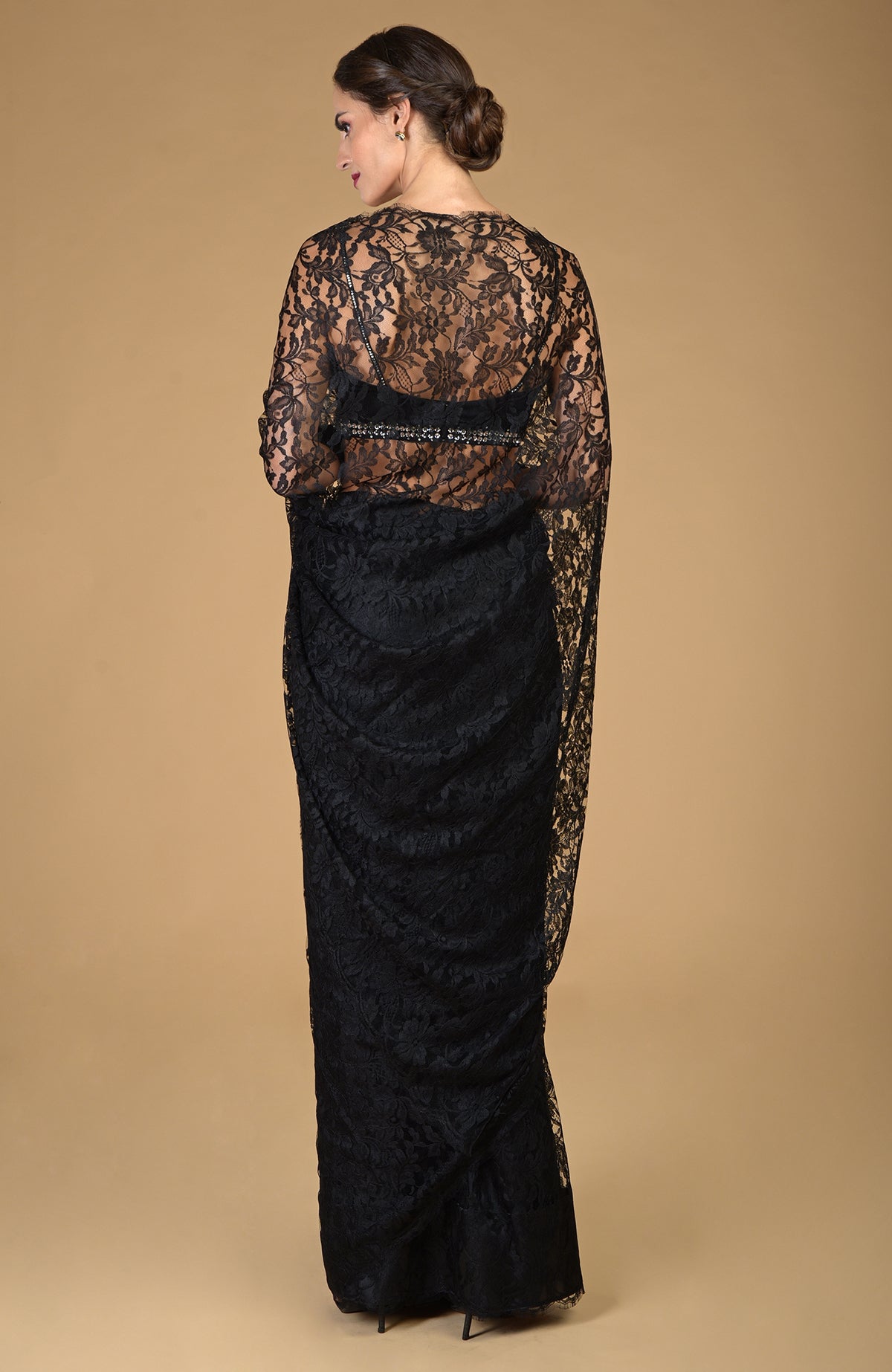 A woman models a black French Chantilly lace saree with an embellished blouse.